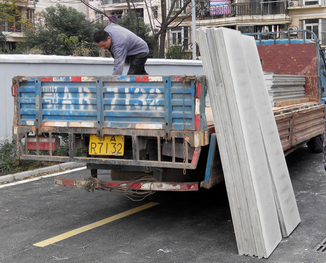 輕質(zhì)墻板運(yùn)往施工現(xiàn)場(chǎng)，工人正在卸載輕質(zhì)隔墻板